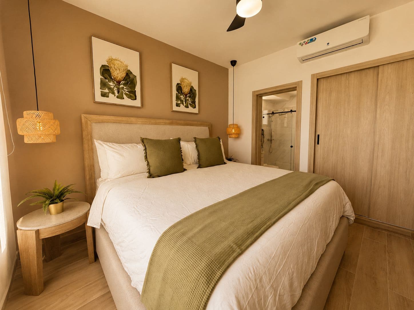 Habitación estilo hotel con cojines verdes y cuadros botánicos